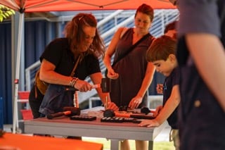 Adults and children working together on a leather stamping activity at Boxyard RTP's 'Live at Boxyard' event.